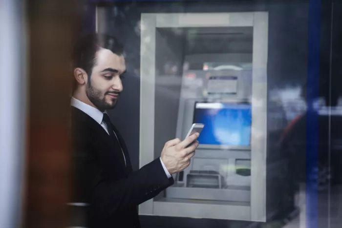 ATM készülék előtt áll egy férfi
