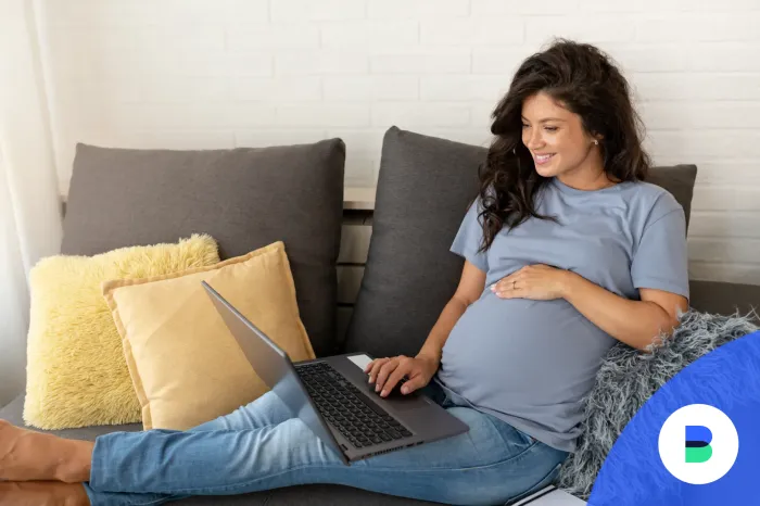8 hónapban lévő terhes anyuka babaváró hitelről olvas laptopon