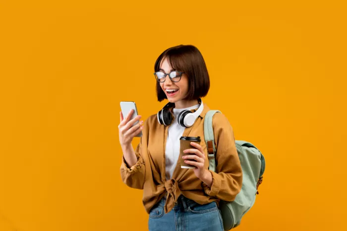 Fiatal lány mosolyogva nézi a mobilján a bankja költségelemzését
