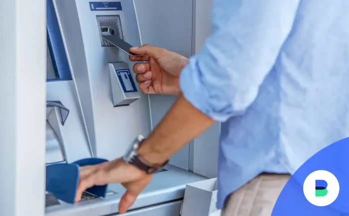 Férfi ATM-be bedugja a kártyáját és megadja a PIN kódját befizetéshez