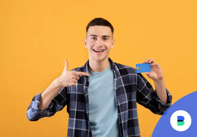 Fiú mosolyog bankkártyával a kezében