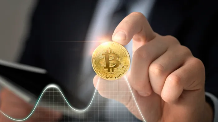 Mi az a Bitcoin? Jelentése, működése és befektetési szerepe férfi kéz bitcoin érmét tart diagrammal