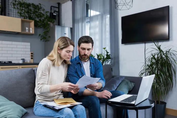 Mikor éri meg az adósságrendezés? pár otthoni környezetben laptop előtt dokumentumokat vizsgál