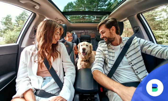 Boldog család autózik a kutyájukkal akik támogatást vettek az autó megvásárlásához