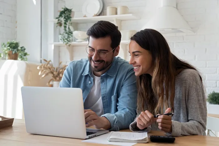 Egyre több fiatal választja az öngondoskodást Fiatal mosolygós pár laptop előtt