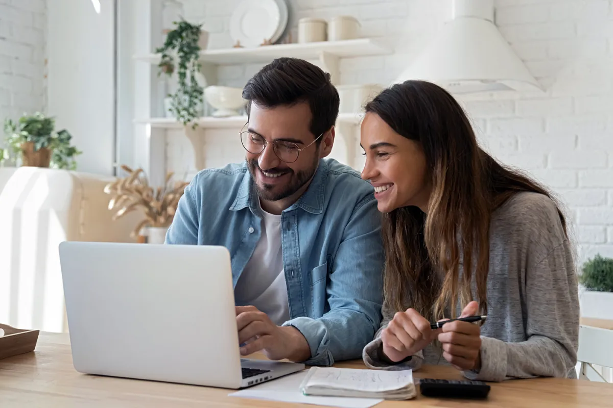 Fiatal mosolygós pár laptop előtt