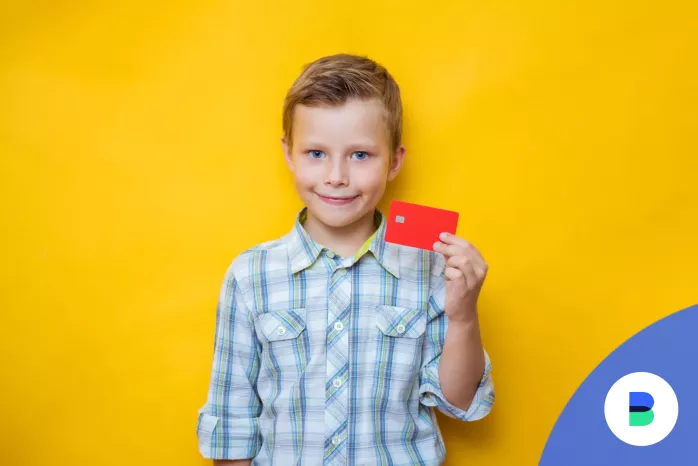 Iskolás fiú egy bankkártyát fog a kezében