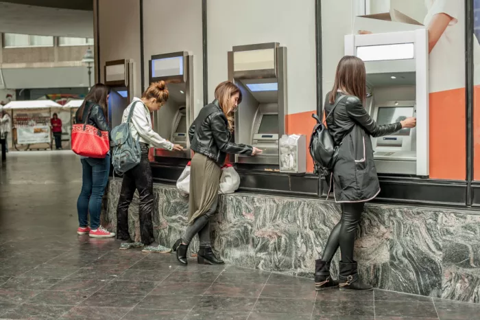 Több ember használ befizető ATM-et egy pályaudvaron