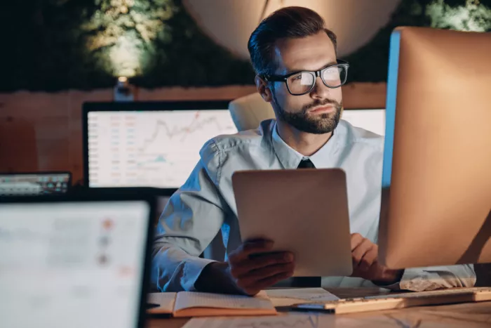 Szemüveges üzletember a devizaszámla egyenlegét nézi monitoron