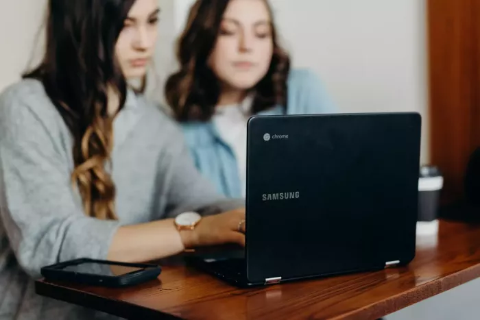 Két diák lány nézi a bankszámlákat egy laptopon