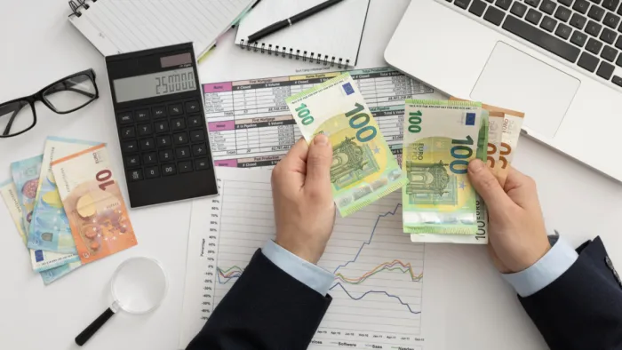 Egy év alatt 15 százalékkal nőtt a lakosság értékpapírvagyona íróasztalon kimutatások számológép laptop és euró bankjegyeket számolgató kéz