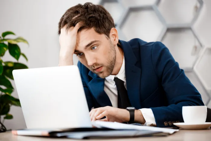 ideges fiatal férfi a laptopja előtt 