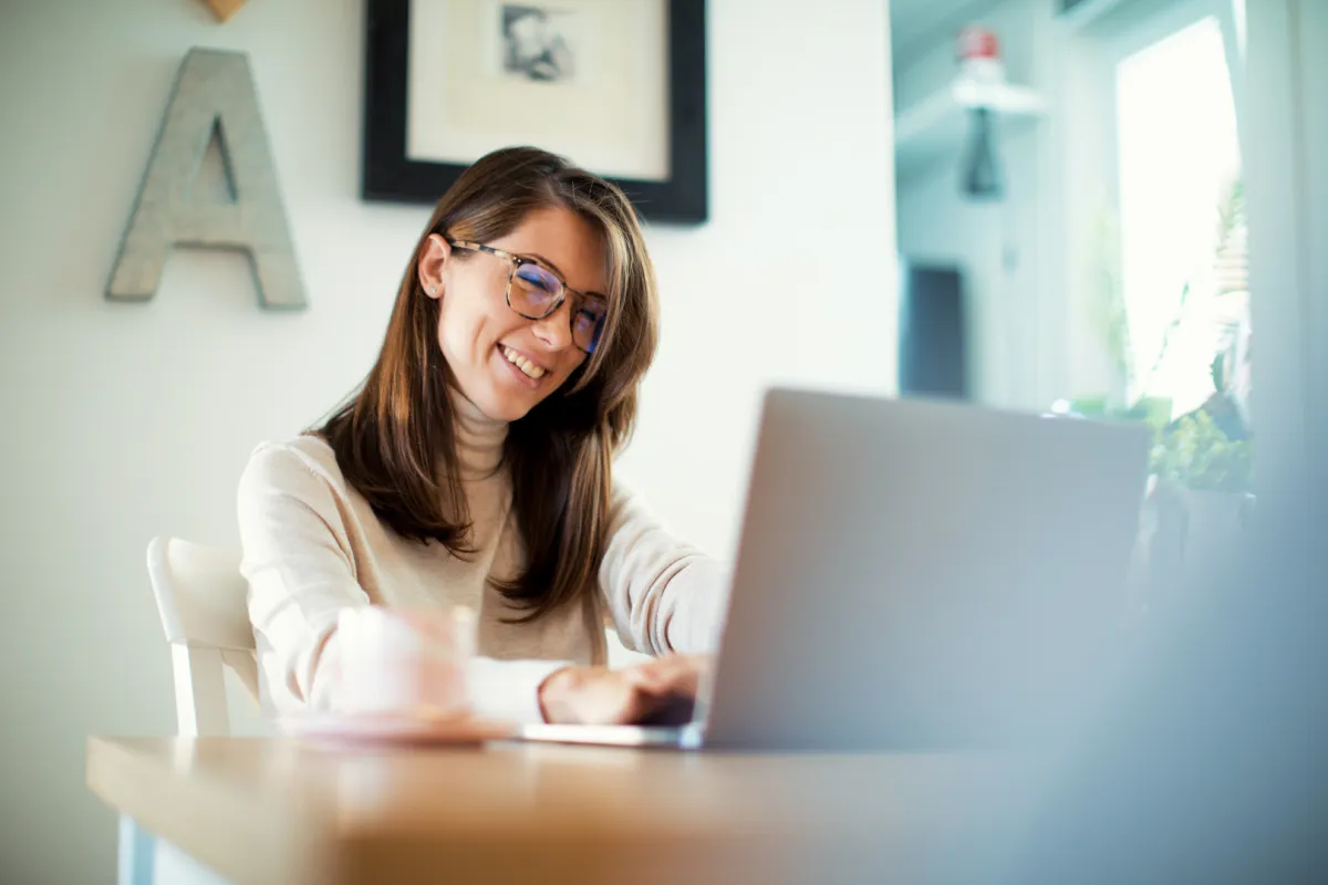 ingyenes bankszámla online nyitása laptop előtt ülő boldog nő