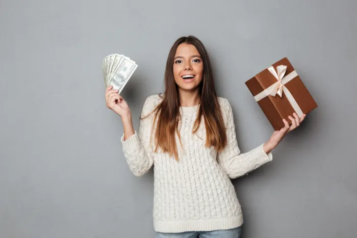 Elindult a karácsonyi kamatverseny: Az OTP ismét olcsóbbá tette a személyi kölcsöneit boldog csinos barna lány pénzköteggel és ajándékdobozzal