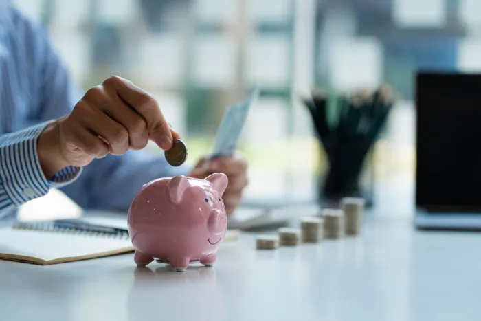 malacperselybe érmét dobó férfi irodai környezetben pénzérmékkel, bankjeggyel