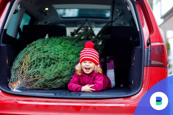 Autóban mosolyos a kislány karácsonyfa mellett