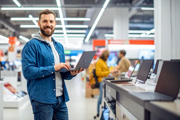 laptopot tartó fiatal férfi szaküzletben