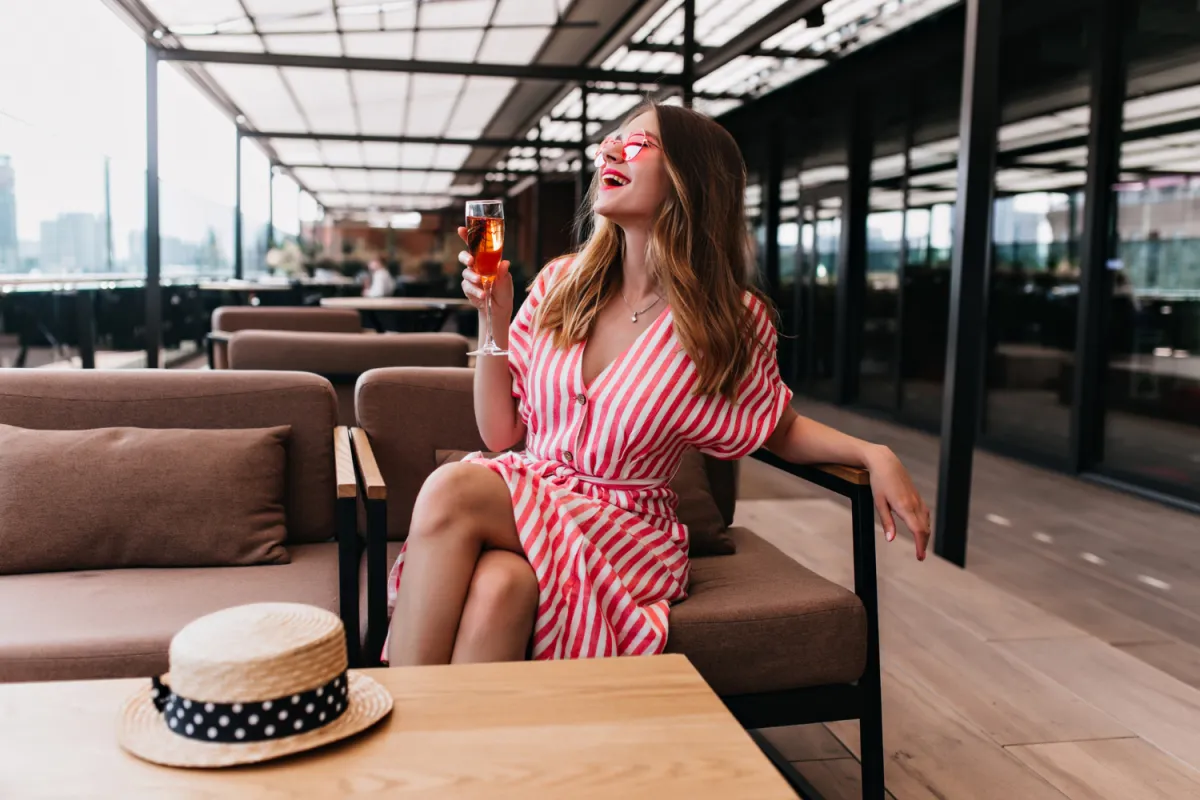 csinos nő pezsgővel prémium airport loungban várja a nyaralást