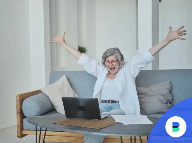 Boldog nyugdíjas, aki a számítógép előtt ülve örömmel látja, hogy milyen sok nyugdíj-megtakarítása gyűlt össze a Prémium Nyugdíjpénztárban