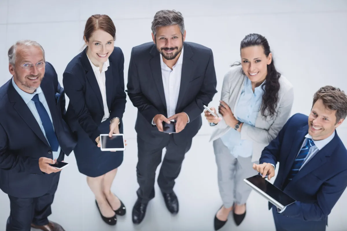 business casual öltözetű szakértők digitális eszközeikkel a kezükben