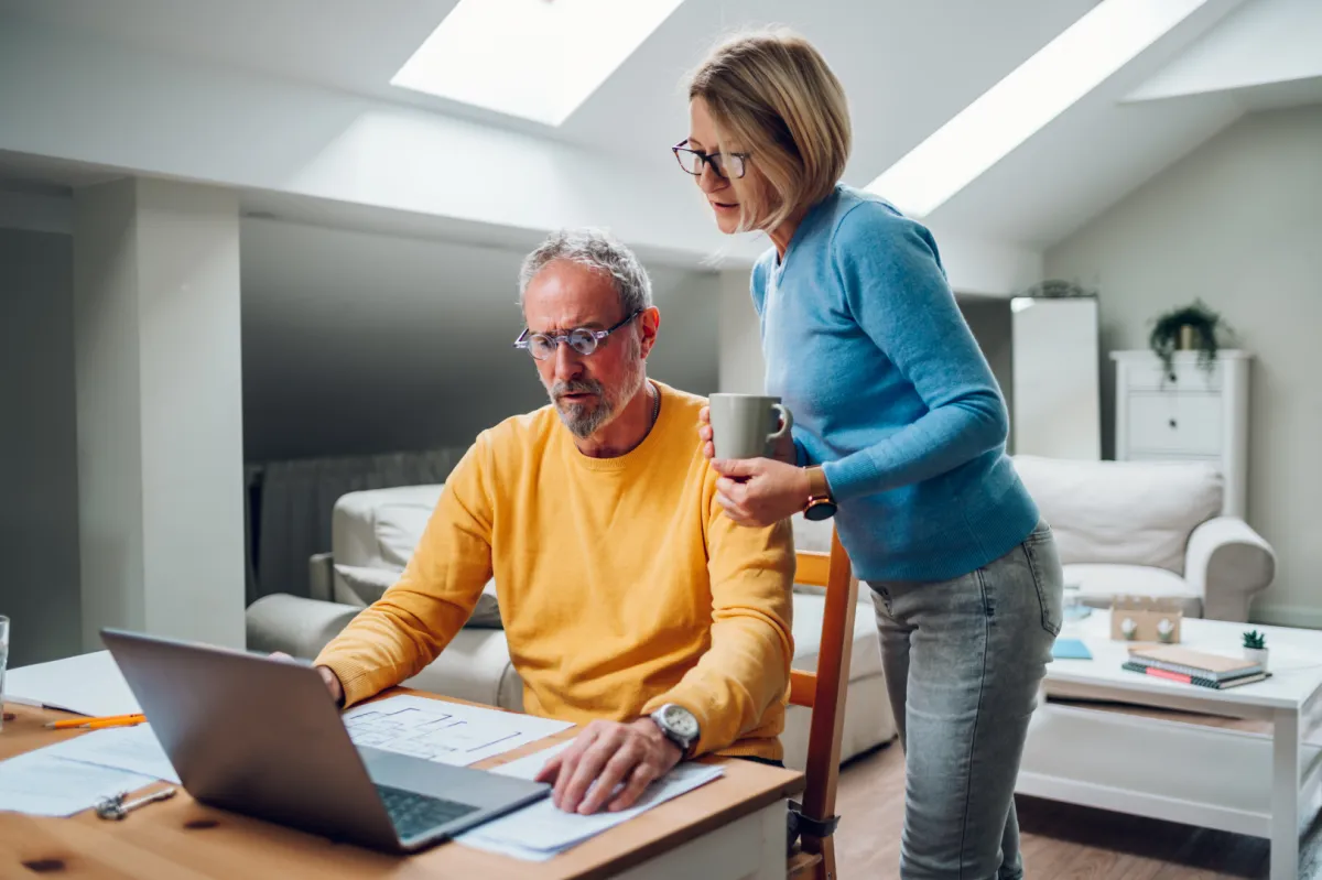 Befektető házaspár laptopon nézi a befektetéseik százalékos értékét