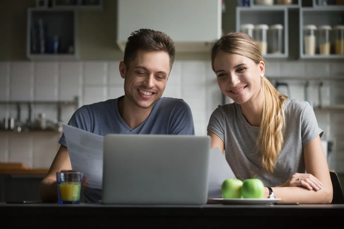 laptopon ügyet intéző boldog fiatal pár