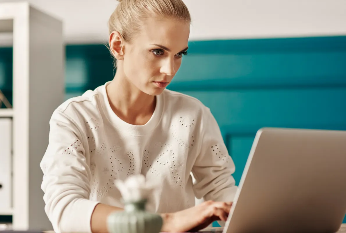 szép szőke nő laptopon bejelentést olvas