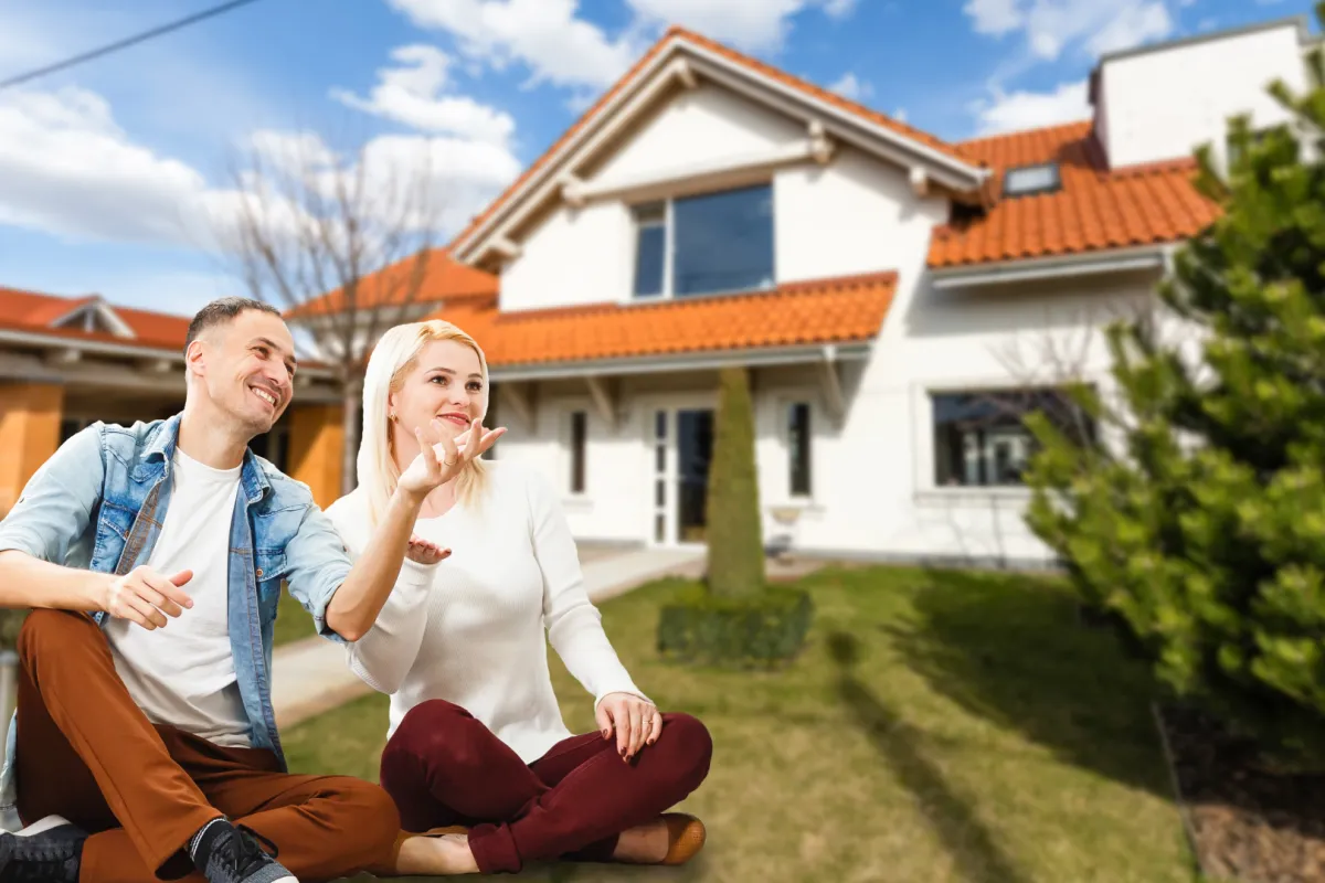 Egy pár az új háza előtt ül