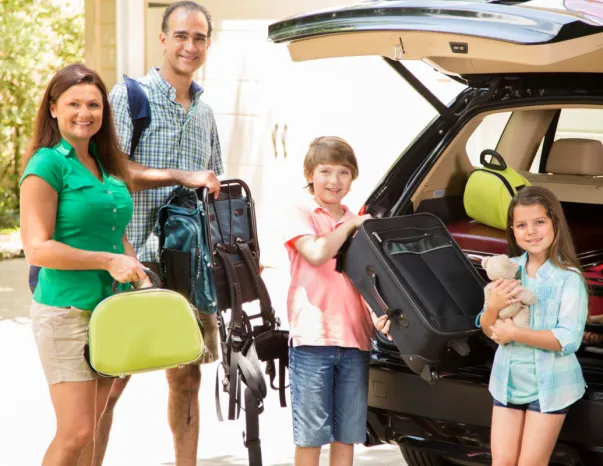 utazásra induló család bepakol a csomagtartóba